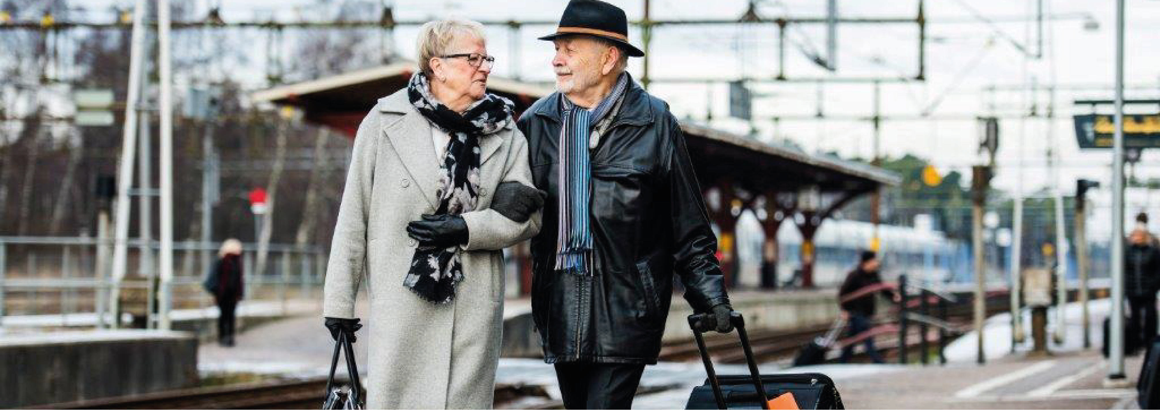 bild på äldre par med järnvägsstation i bakgrunden